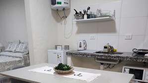 A modern kitchen with a white countertop, a water heater, a coffee maker, and a small refrigerator.
