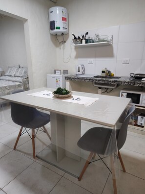 A modern kitchen with a white countertop, a water heater, a coffee maker, and a small refrigerator.