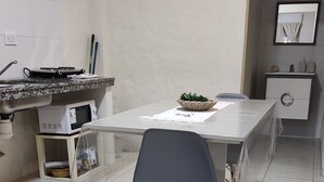 A modern kitchen with a dining table, chairs, a microwave, and a sink.