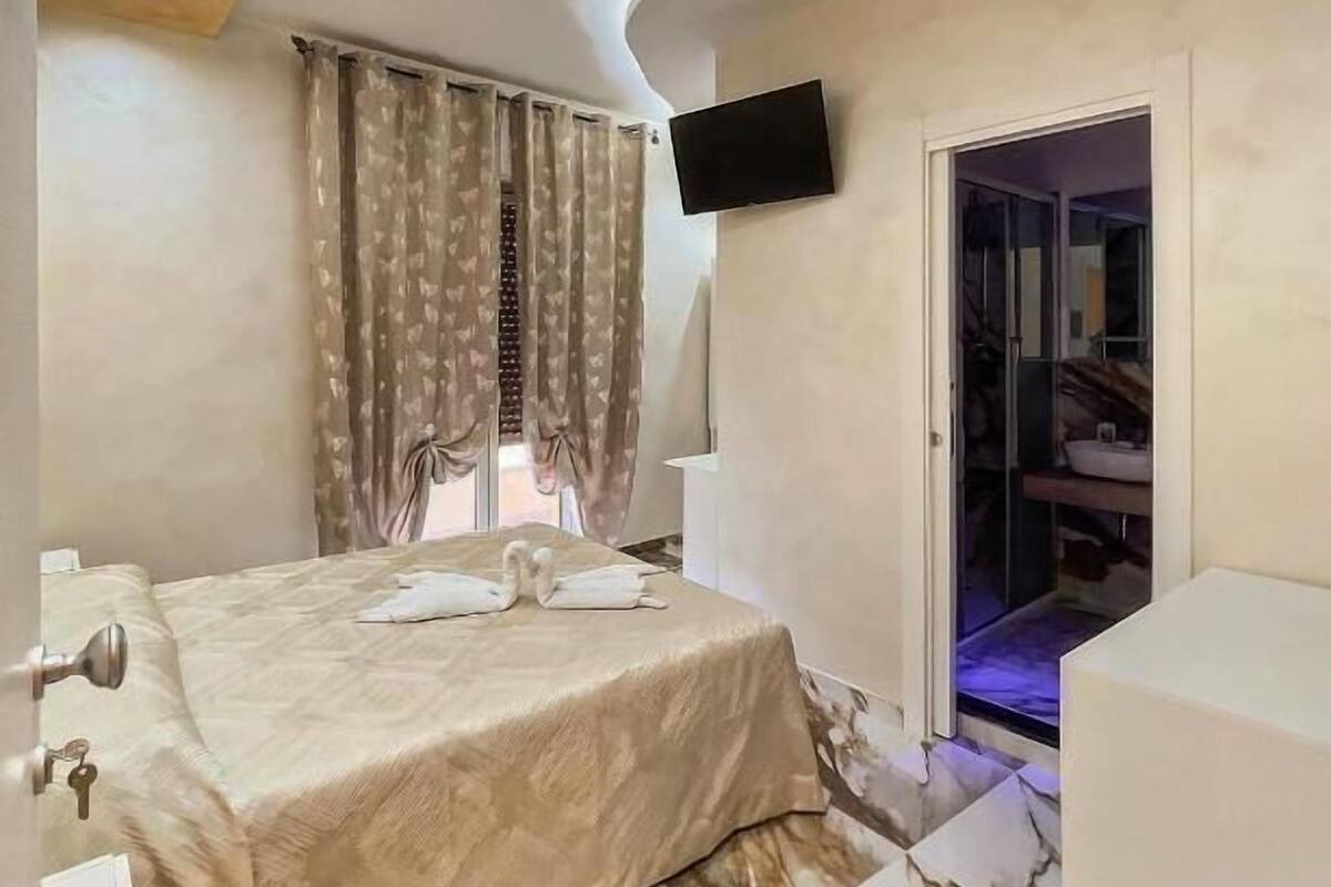 A modern bedroom with a bed, a TV, and a sliding door to a bathroom.