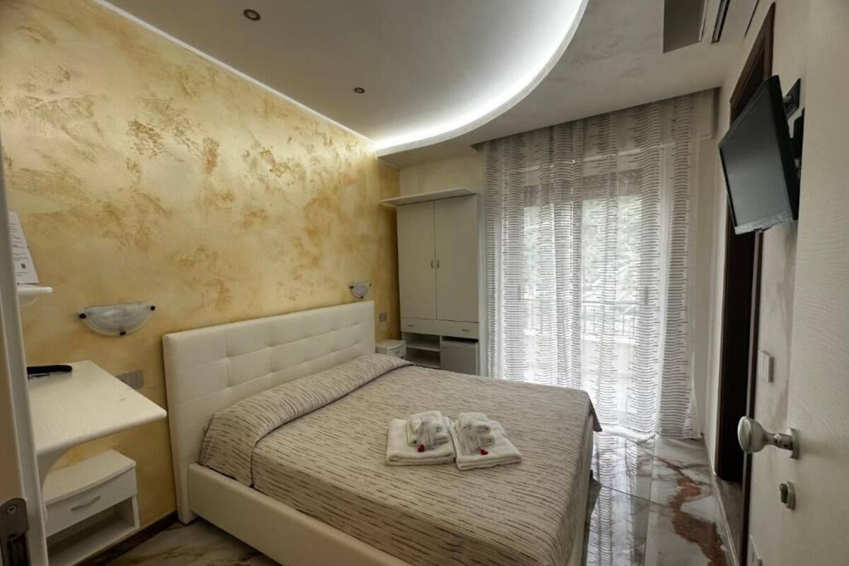 A modern bedroom with a large bed, a bedside table, a wardrobe, and a television.