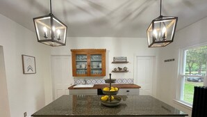 Una cucina con isola centrale, due luci a sospensione, un armadietto in legno e una finestra con vista.