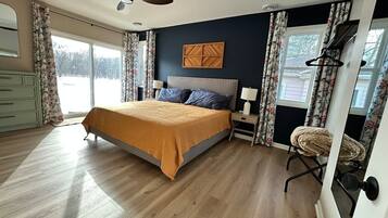 A bedroom with a bed, a nightstand, a chair, a ceiling fan, and a window with curtains.