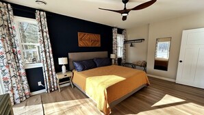 A bedroom with a bed, two bedside tables, a ceiling fan, a window with curtains, and a door. - Escape to The Riverfront Hideaway (Momence)