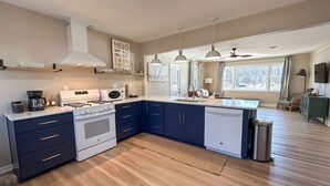 A modern kitchen with a stove, oven, and dishwasher, wooden flooring, and pendant lights. - Escape to The Riverfront Hideaway (Momence)