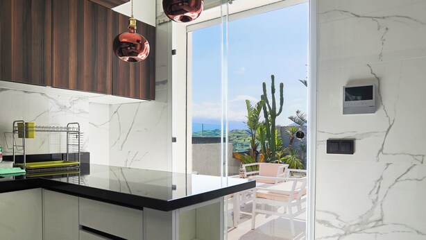 A modern kitchen with a glass countertop, wooden cabinets, and a view of the outdoors. - Villa Perle mémorable séjour vous attendent (Tetouan)