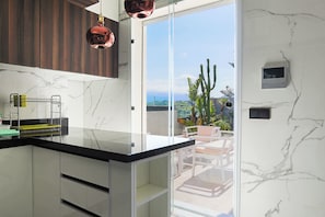 A modern kitchen with a glass countertop, wooden cabinets, and a view of the outdoors.