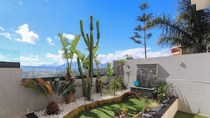 A rooftop garden with various plants, a small water feature, and a view of the cityscape. - Villa Perle mémorable séjour vous attendent (Tetouan)