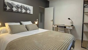 Een moderne slaapkamer met een bed, een bureau en een stoel.