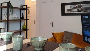 Een moderne woonkamer met een salontafel, decoratieve kommen, een boekenkast en een tv met een streamingdienst interface.