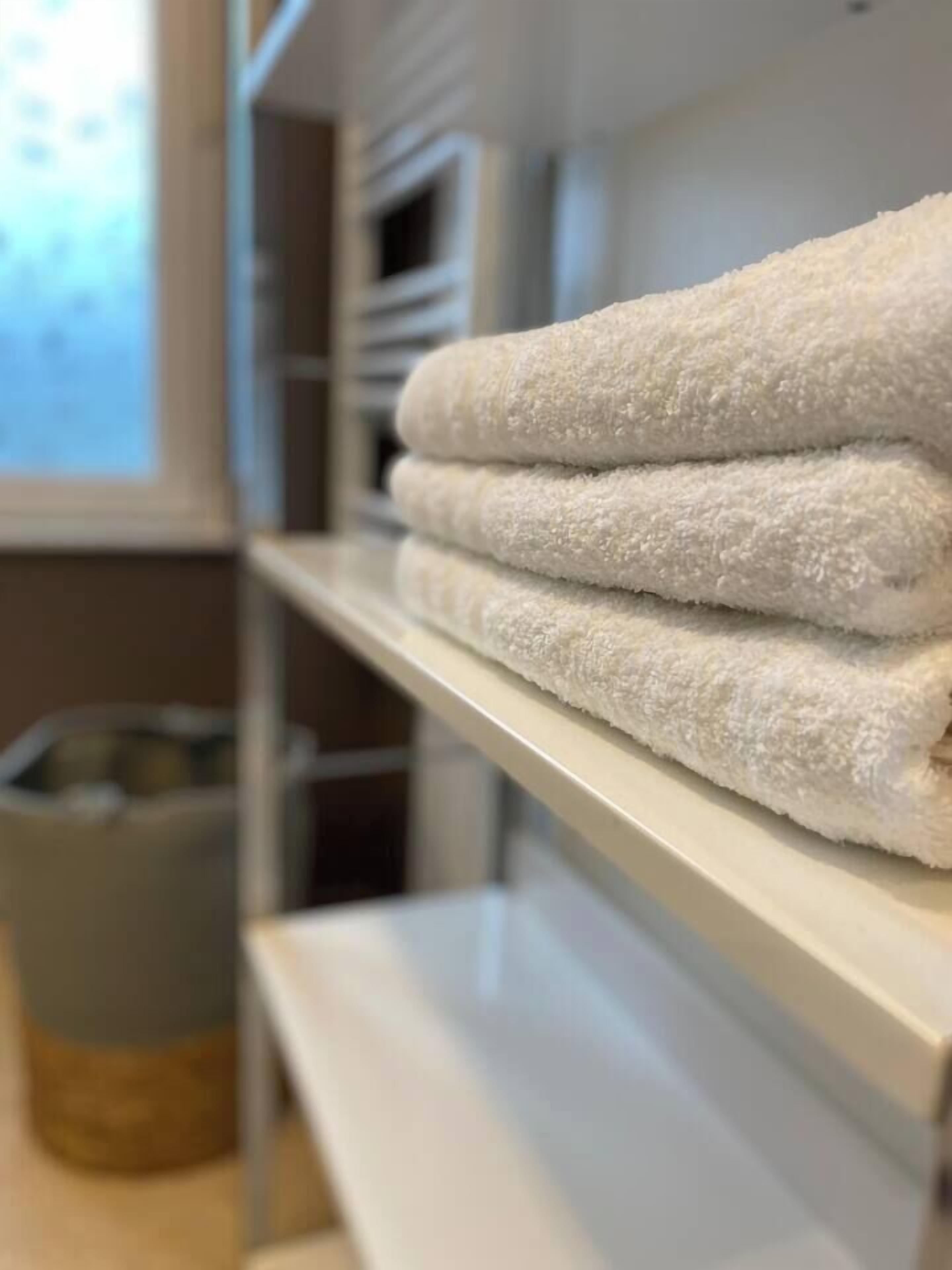 Ein Stapel weiße Handtücher auf einem Regal in einem Zimmer.