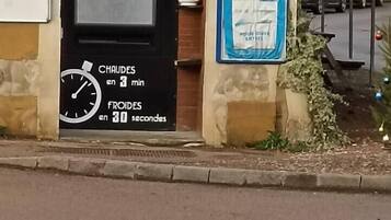 Un edificio con un letrero que dice "PIZZAS ARTISANALES 24h/24" y un reloj que muestra temperaturas.