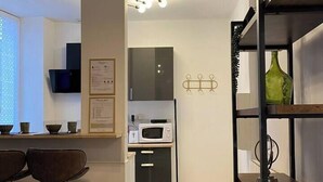 Een moderne keuken met een magnetron, een zwart kastje en een bar voorzien van krukken.