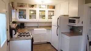 A compact kitchen with white cabinets, a microwave, a stove, and a sink.