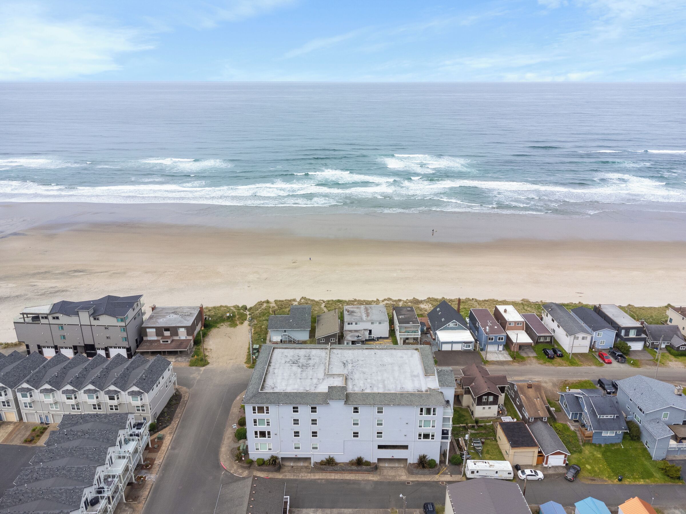 Zona residencial costera con playa, casas y una carretera.
