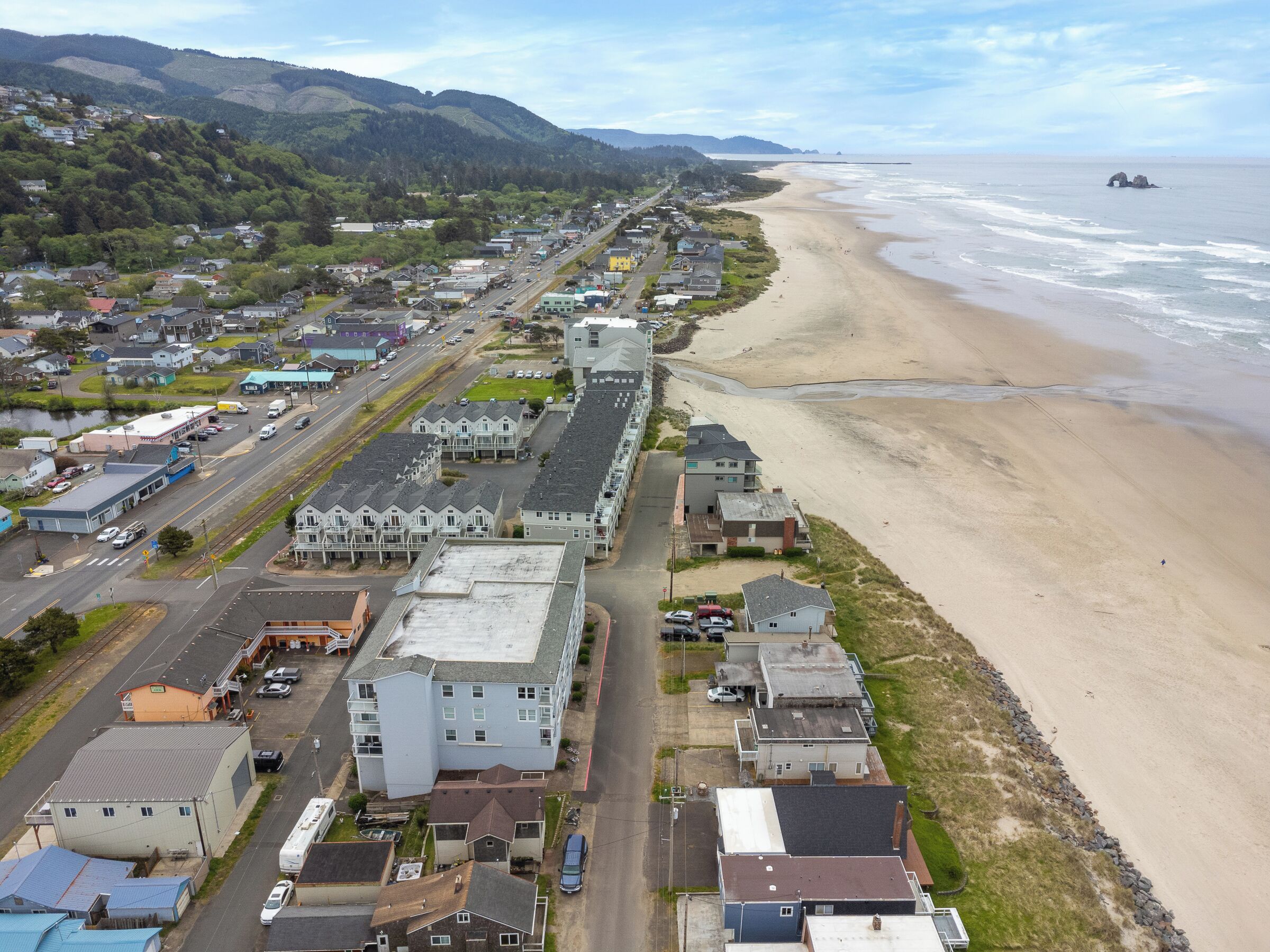Un pueblo costero con una combinación de edificios residenciales y comerciales, una playa y vistas al océano.