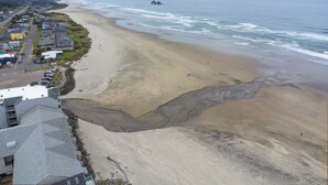 Eine Küstenstadt mit einem breiten Sandstrand, einer felsigen Küstenlinie und Blick auf den Ozean.