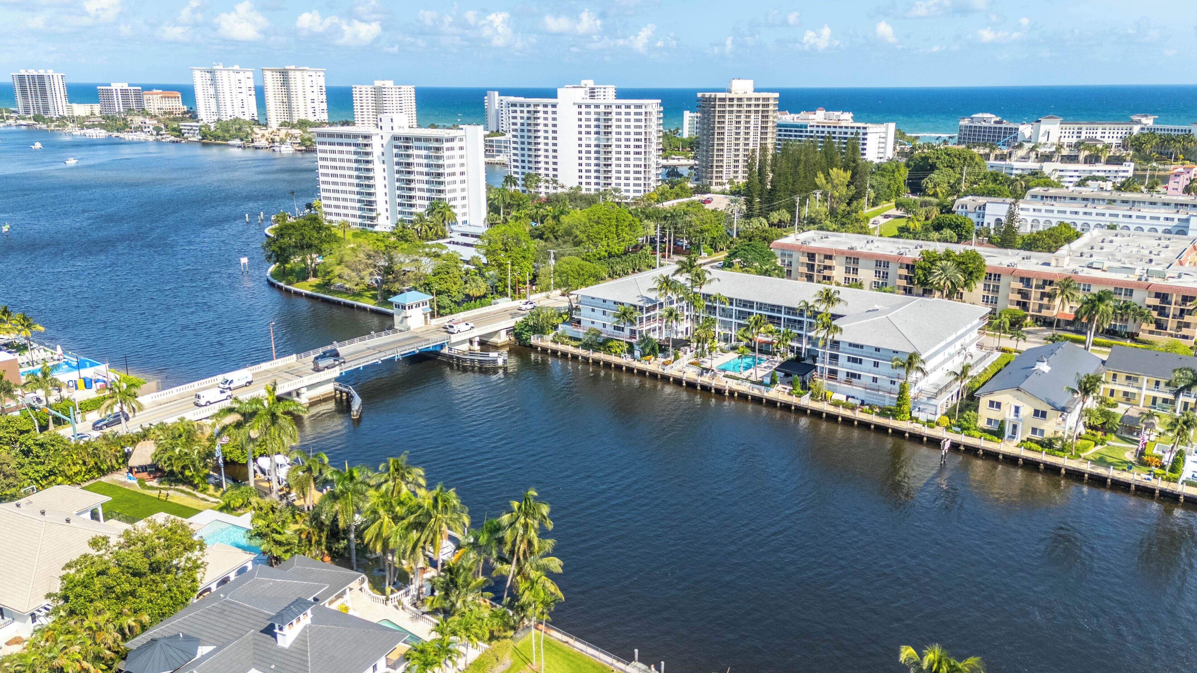 Un paisaje urbano costero con rascacielos, un puerto deportivo y un puente que conecta dos zonas.