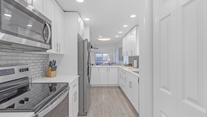 A modern kitchen with white cabinetry, stainless steel appliances, and a tiled backsplash. - Top Floor Corner Unit: 2BR Waterfront with Stunning Intracoastal Views (Boca Raton)