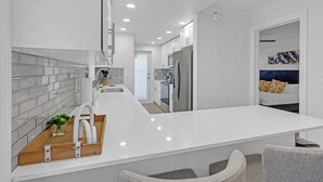 A modern kitchen with white countertops, stainless steel appliances, and a central island. - Top Floor Corner Unit: 2BR Waterfront with Stunning Intracoastal Views (Boca Raton)