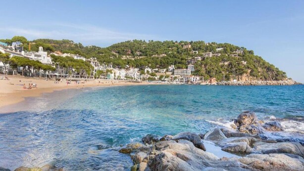A beach with clear water, rocky shoreline, and buildings on a hillside. - Apartment in Llafranc Near Sandy Beach (Palafrugell)