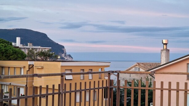 Un quartier résidentiel situé sur la côte, avec des bâtiments, une clôture en bois et une vue sur la mer.
