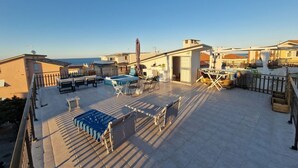 Une terrasse sur le toit avec une piscine, des chaises longues et un espace repas.