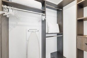 A walk-in closet with a hanging rack, shelves, and a built-in ironing station.