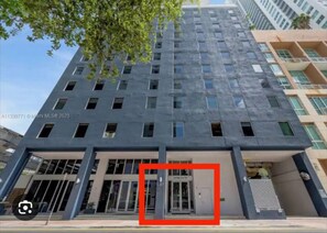 A modern building with a flat facade, multiple windows, and a ground-level entrance with glass doors. - Chic Downtown Studio With Rooftop Pool and Gym (Miami)