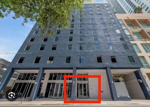 Un edificio moderno con fachada plana, múltiples ventanales y acceso a nivel de calle con puertas de vidrio.