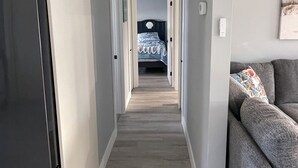 Un couloir étroit, avec un réfrigérateur sur la gauche, un canapé sur la droite et un lit au fond.