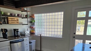 A kitchen with white cabinets, a dishwasher, a coffee maker, and a window with a view of the outside.