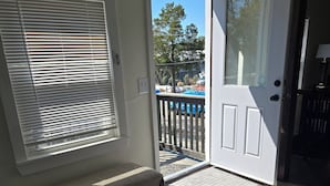 A room with a bench, a door, and a view of a blue vehicle outside.