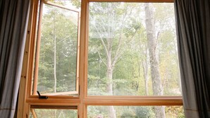 A bedroom with a skylight, large windows, and a view of trees.
