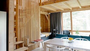 A wooden cabin interior with a dining area, a sofa, and a bed.