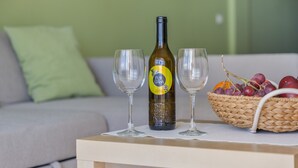 Een fles wijn, twee glazen en een mand met fruit op een tafel.