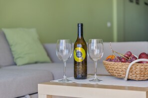 Une bouteille de vin, deux verres et un panier de fruits sur une table.