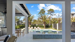 Un patio moderno al aire libre con piscina, sillas de descanso y zona de comedor.