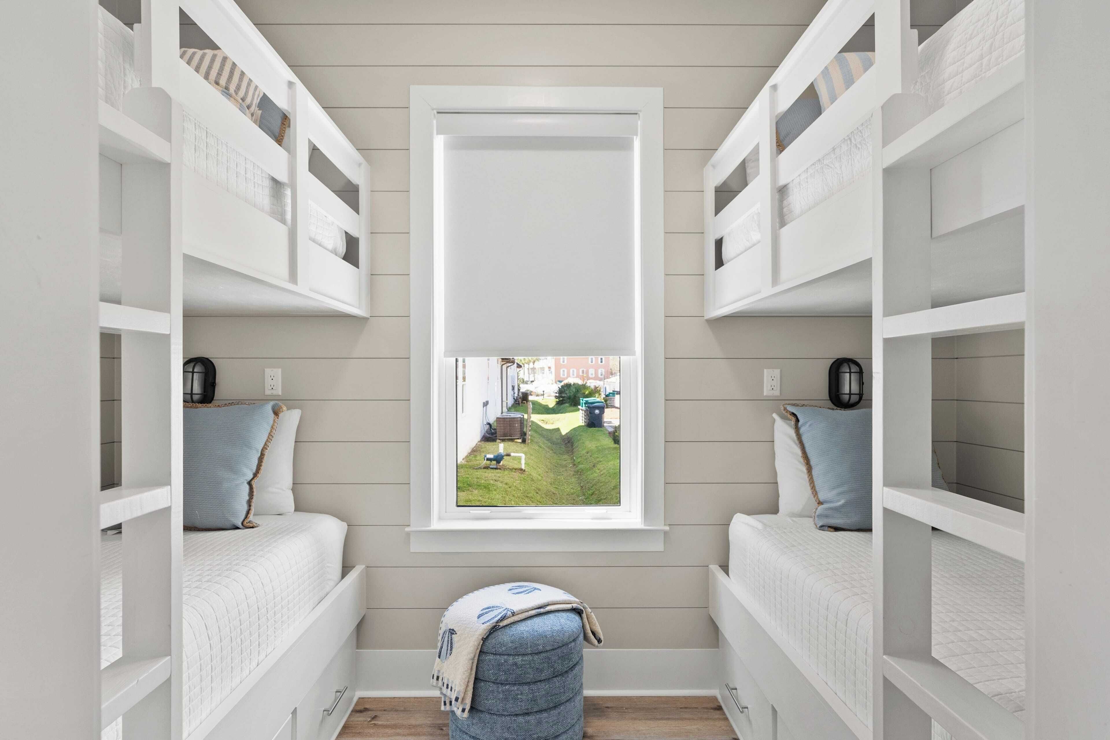 Quarto com beliches, uma janela e vista para o jardim.