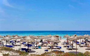 Relax on sun loungers under thatched umbrellas, steps from the clear blue sea.