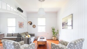 En stue med sofa, to møblerede lænestole, et sofabord og en potteplante.