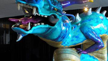 Una gran escultura de dragón, colorido, con cuerpo texturizado en tonos azul y morado, dientes afilados y garras.