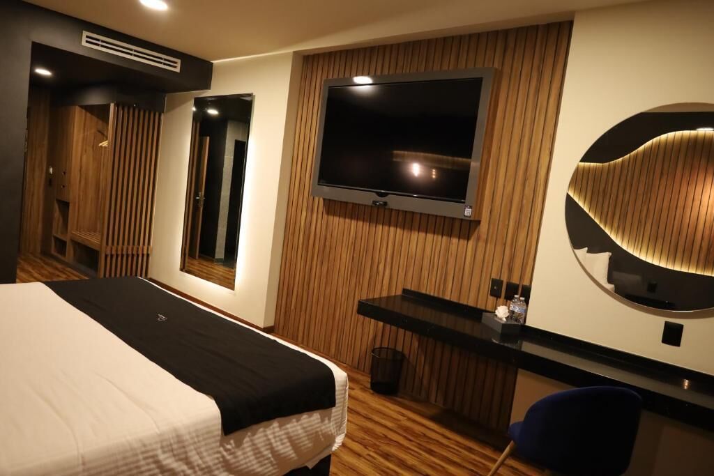 Et hotelværelse med seng, fjernsyn, skrivebord og spejl.