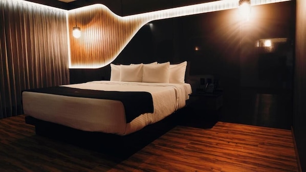 A modern bedroom with a large bed, wooden flooring, and a unique light fixture above the bed. - YORU (El Marques)