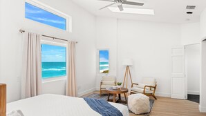 Una habitación de hotel con una cama grande, dos sillas, una mesita y vistas al océano.