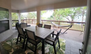 A covered patio with a dining table, chairs, and a hammock.