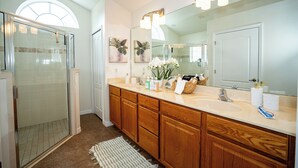 A bathroom with a glass shower enclosure, wooden cabinets, a large mirror with lights, and a window above the shower. - 2 King 2 Twin 1 Queen + Enormous Deck 3 BD Lakeview by Waterfront Park & Events (Clermont)