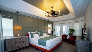 A bedroom with a large bed, a wooden dresser, a red chair, a plant, and a ceiling fan. - 2 King 2 Twin 1 Queen + Enormous Deck 3 BD Lakeview by Waterfront Park & Events (Clermont)