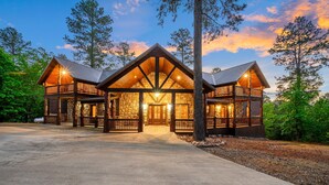 A large log cabin with a central entrance and two side wings, surrounded by trees.