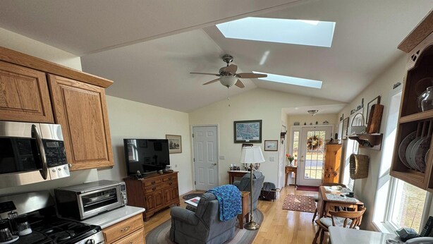 A kitchen with a microwave, toaster, stove, and a ceiling fan.